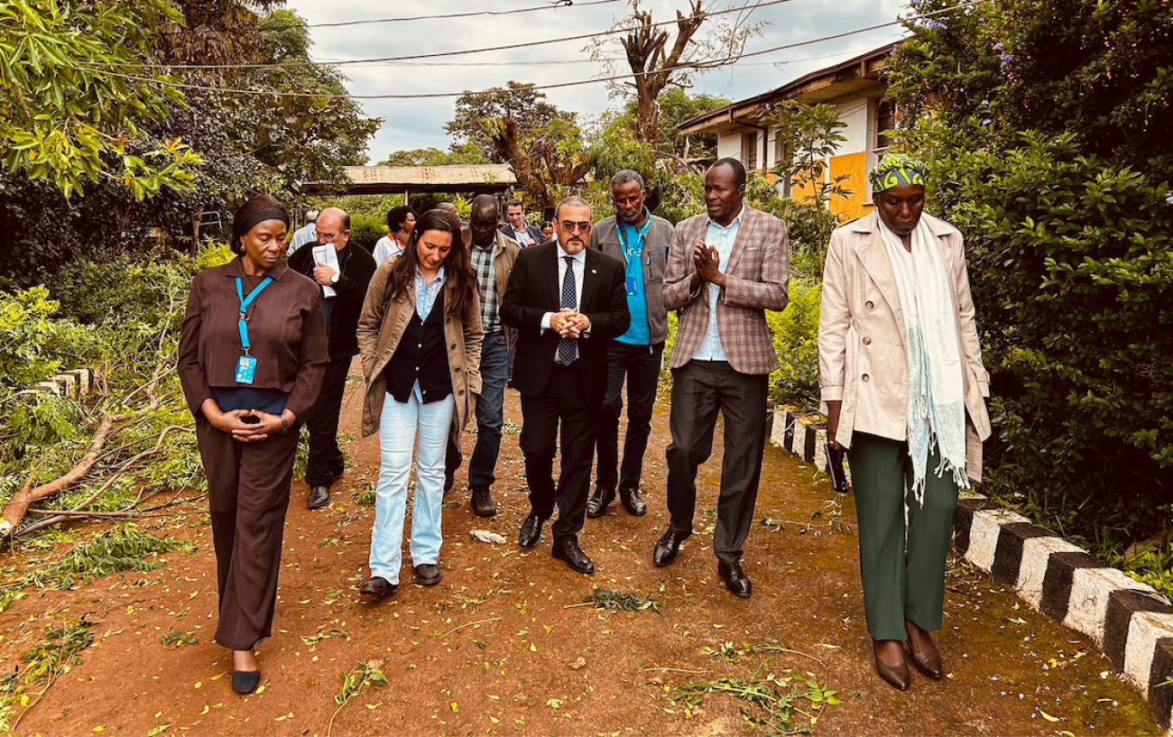 group of people in suits walk along dirt path with tress in the back ground