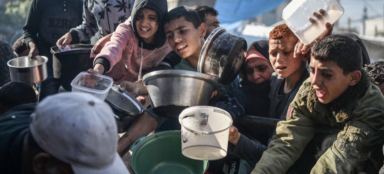 A group of children in Gaza hold out empty bowls and cups