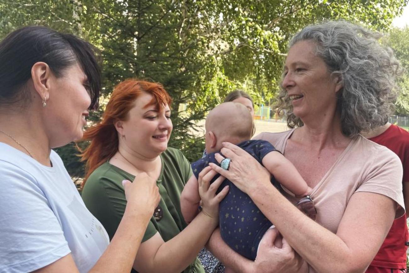 Denise Brown holding a baby while speaking to other women