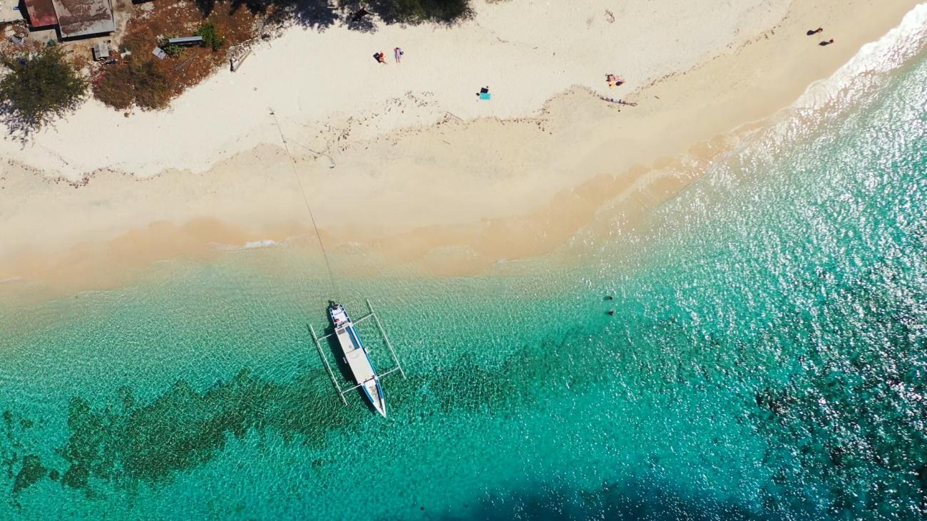 An aerial view of a serene beach setting with a sea plane in the water