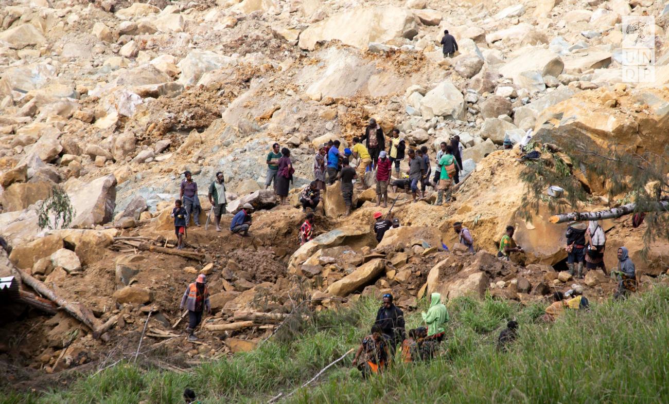 People working on landslides and gathering outside in a devastated area