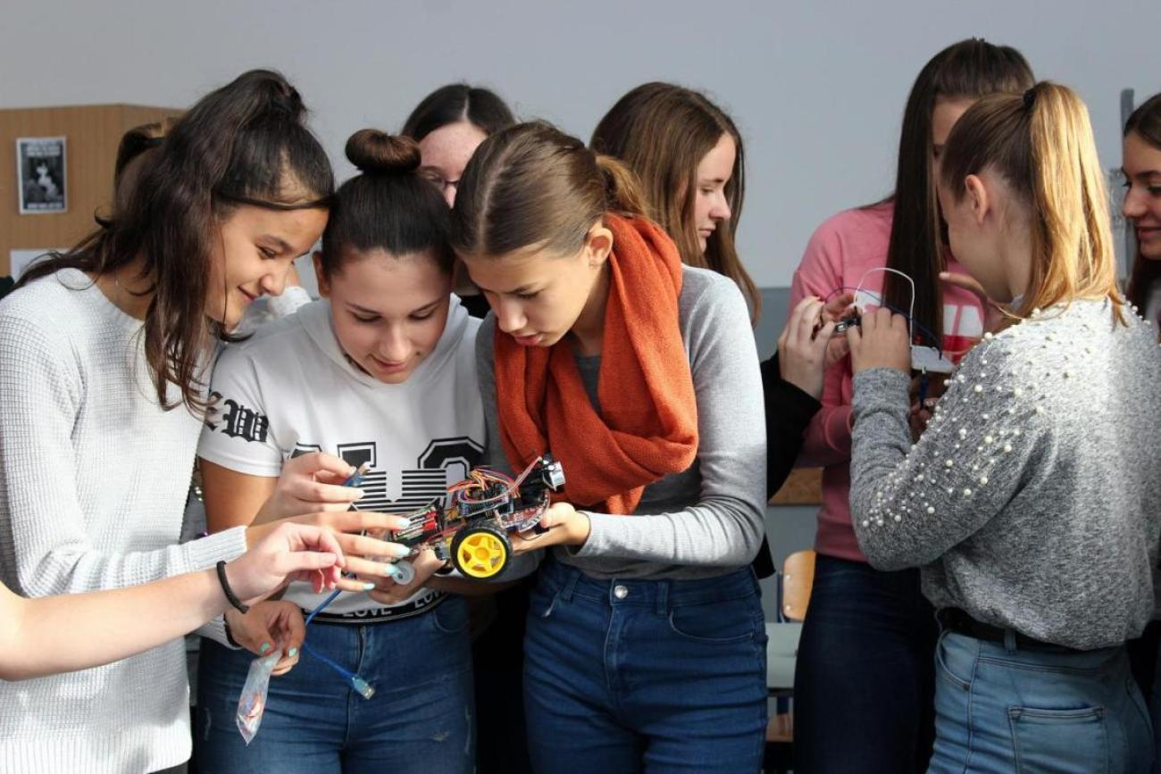 A group of girsl hudled around an innovation