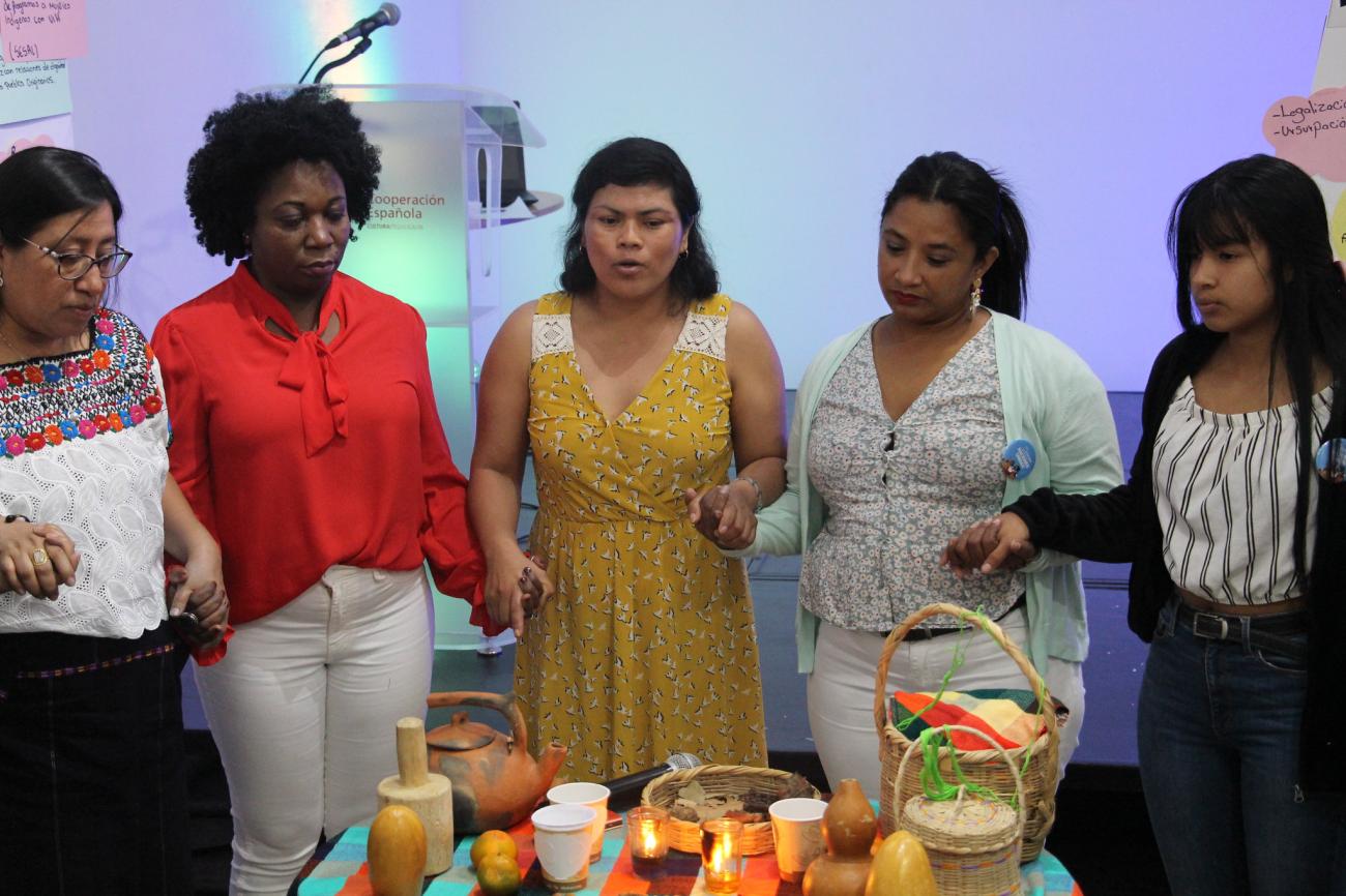 A group of women standing in front of candles and praying