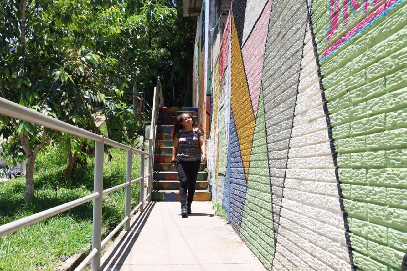 A woman walking down a colourful walkway. She is smiling and looking very carefree
