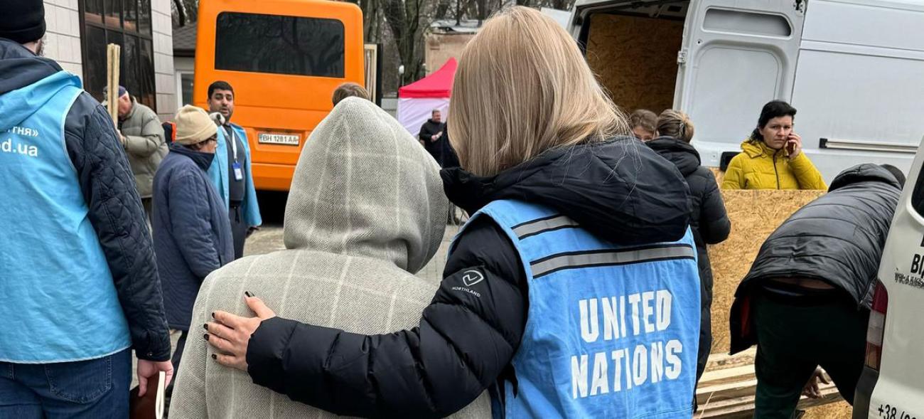 A woman is wearing a UN vest and holding onto a child