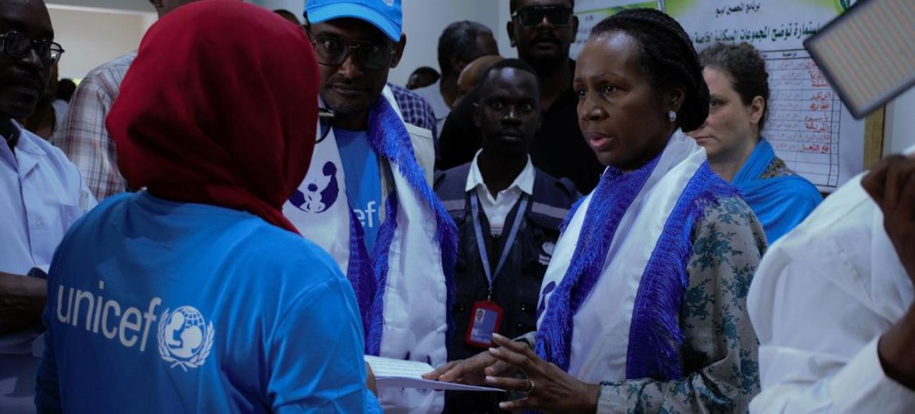 A woman is surrounded by others wearing UN branded clothing and they are all engaging in a conversation