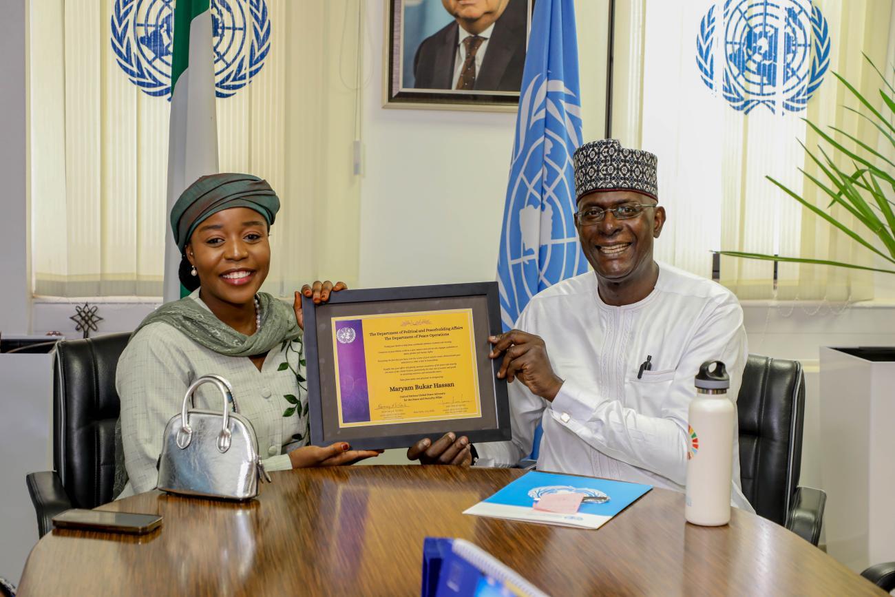 A man and a woman are looking at the camera and smiling they are holding an award between them