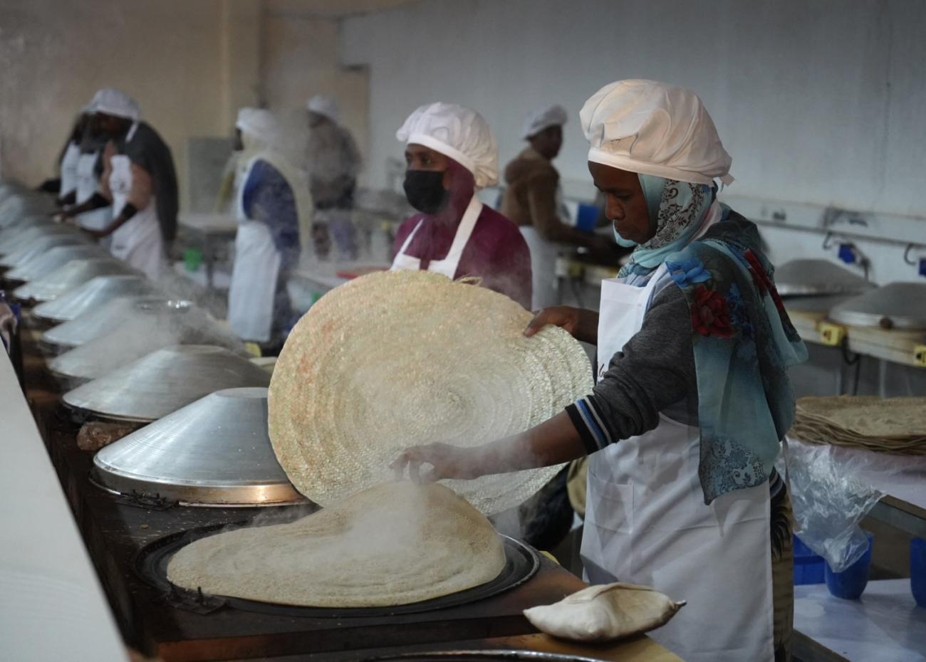A group of women are cooking in a hot steaming room