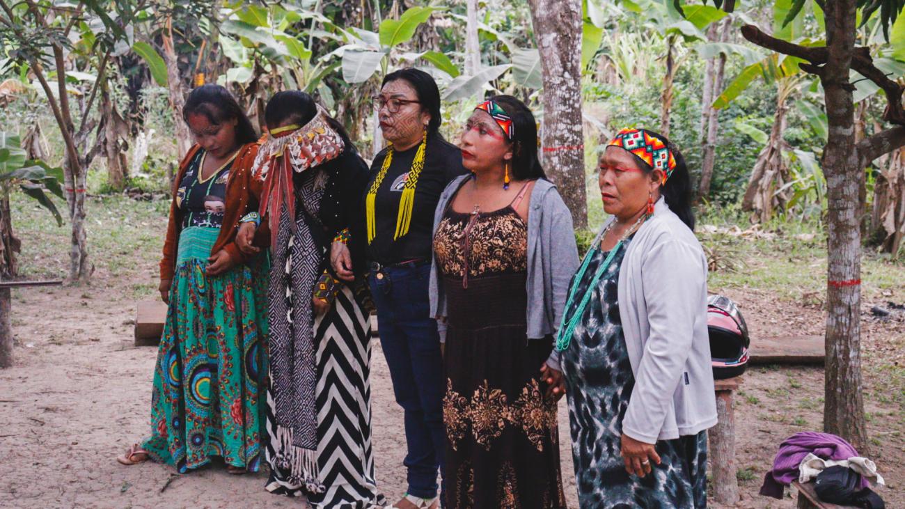 A group of women in traditional dress stand together in an outdoor setting  