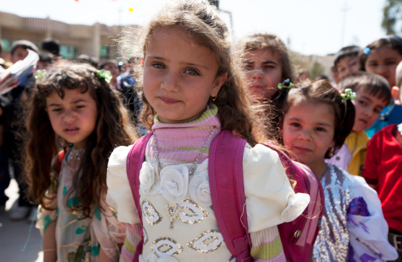 A group of young little girls looking at the camera and smiling in an outdoor setting