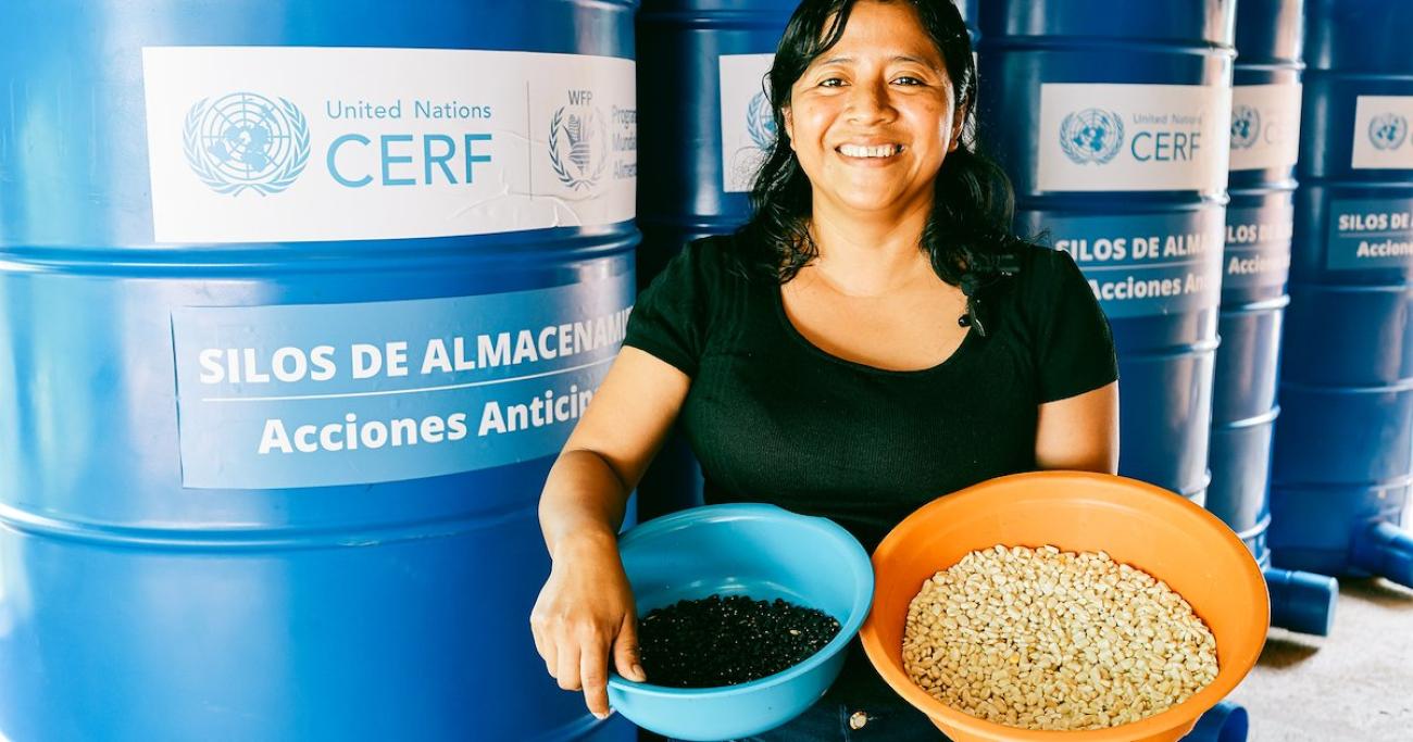 A woman in Guatemala holds two bowls of harvests she reaped.