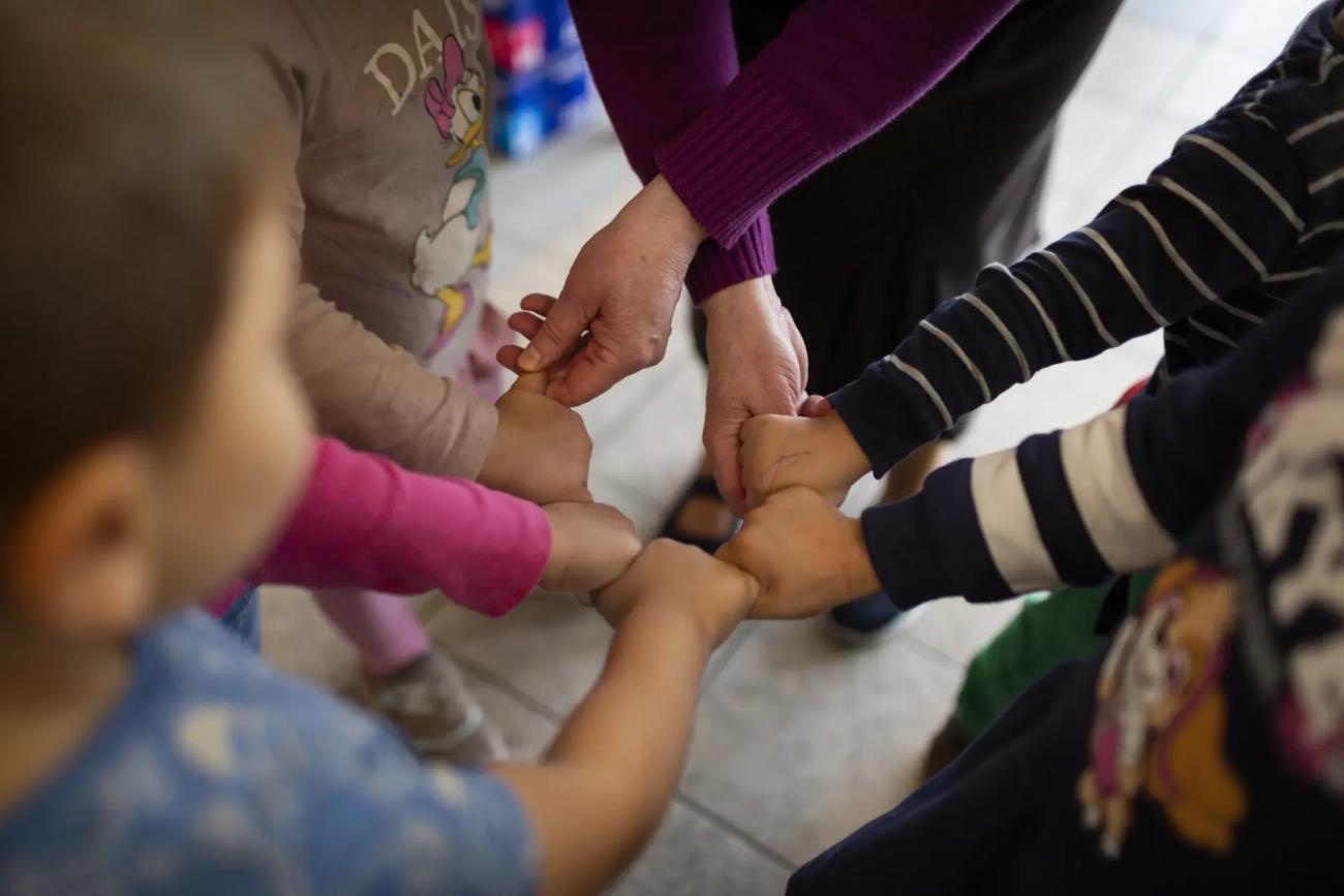 Children join their fists in a circle.