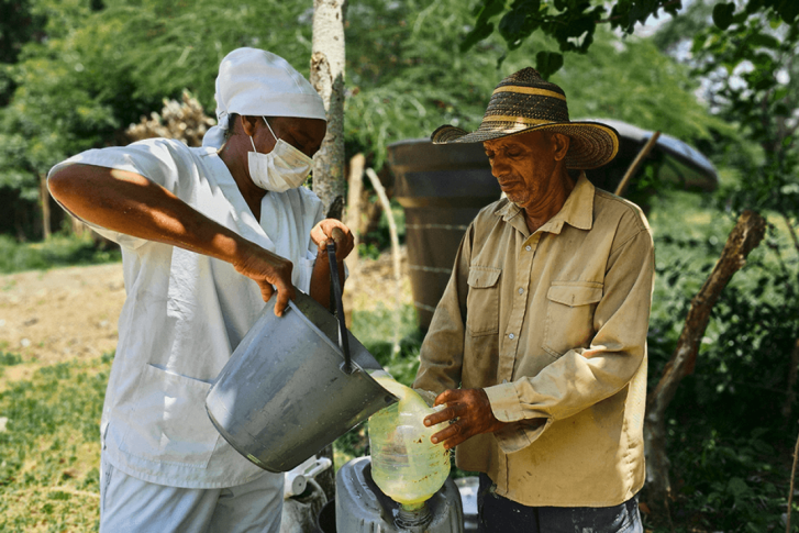 A man pours something into another bucket in an outdoor setting