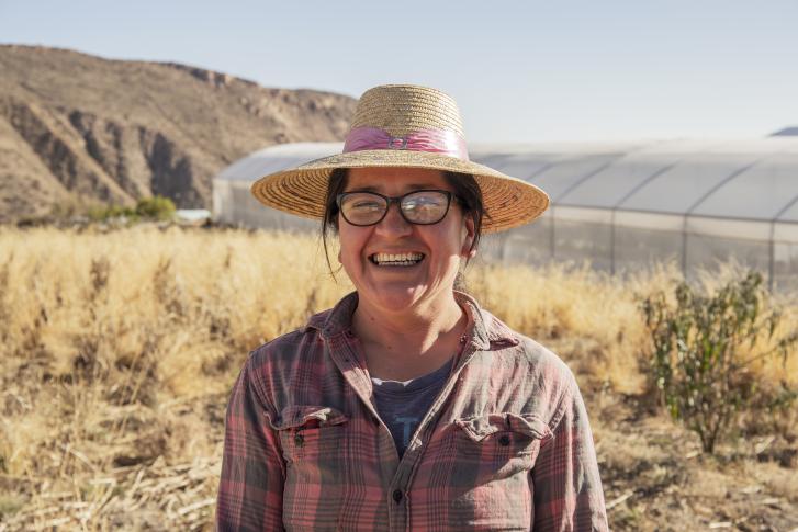 A female Chilean farmer stands on her land.