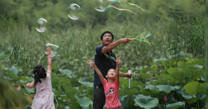 A father and his two young daughters in China play with bubbles.