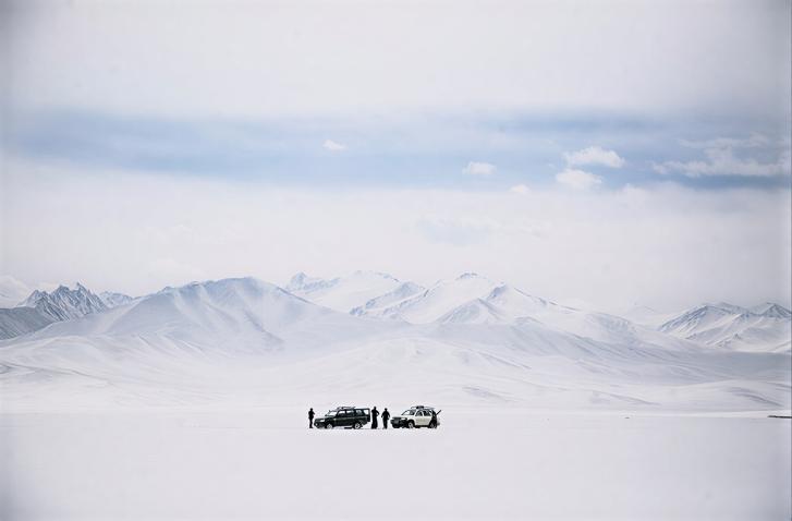 A group of people stand in front of a snowy mountain in Tajikistan.