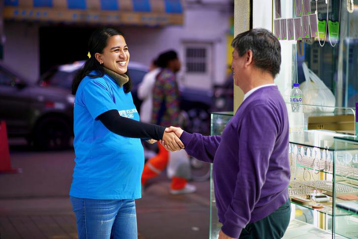A female UN volunteer in Peru shakes hands with a local man. 