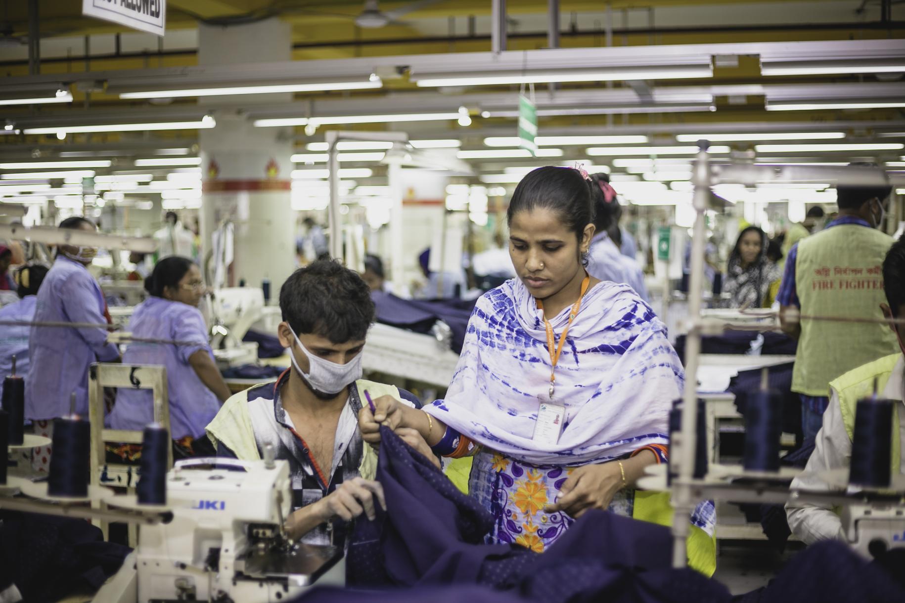 two people working in at a machine in a garment factory 