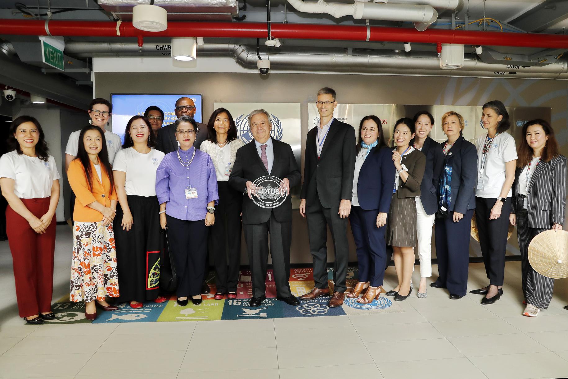 group of people stand posing for a photo with a man in the centre holding an award