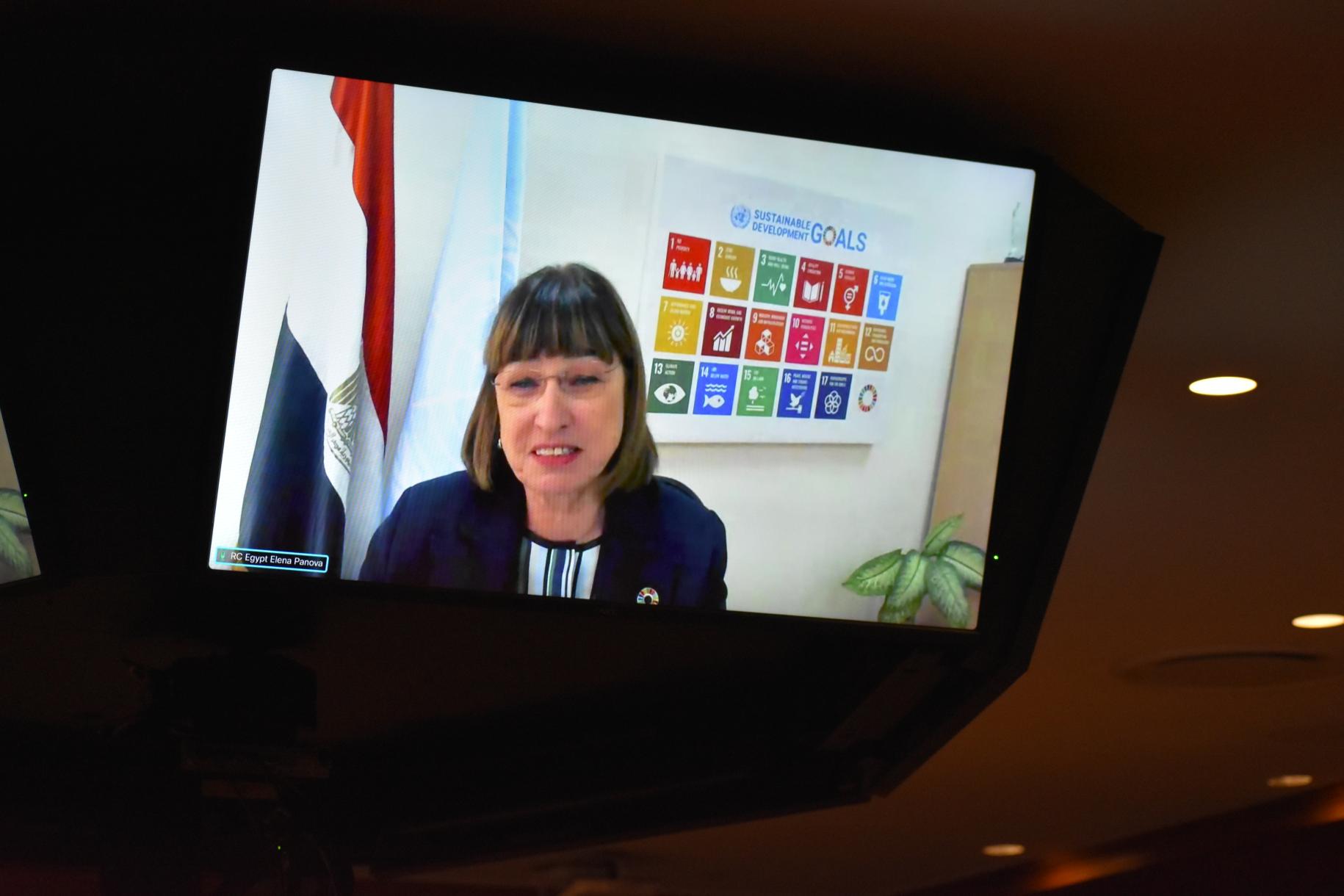 woman in dark suits speaks from a TV screen 