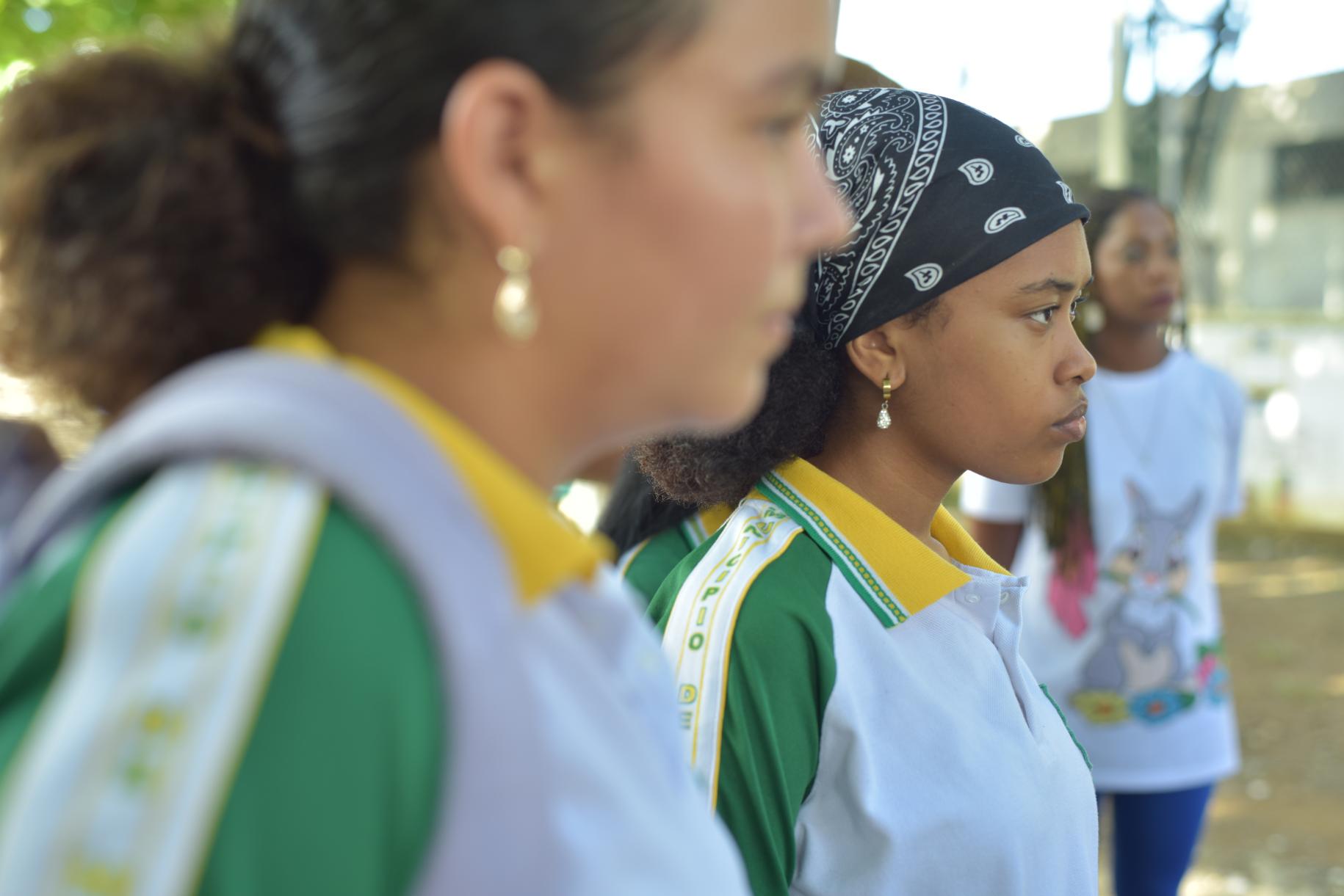 two girls in green and white t-shirts stand side on to the camera 