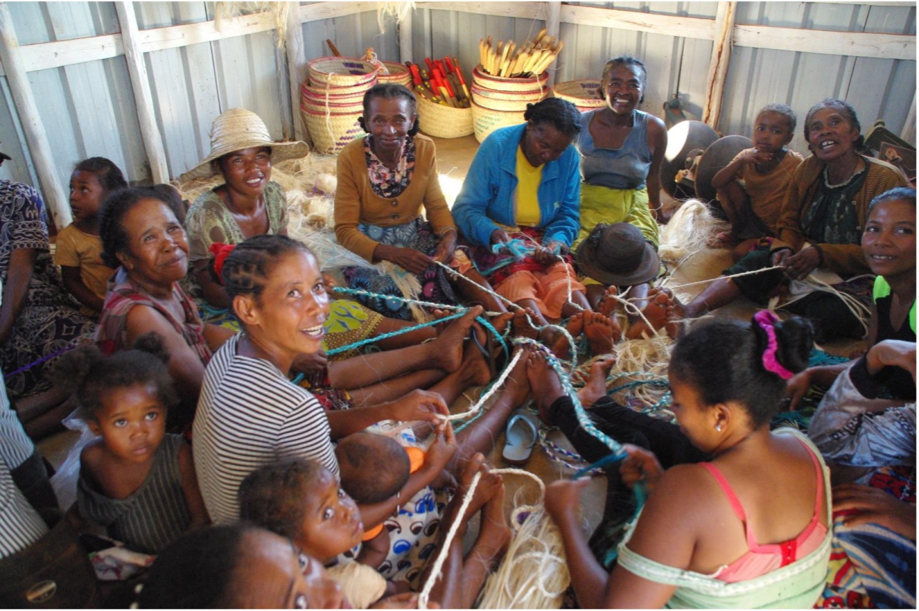 group of women sit on the ground making handicrafts 