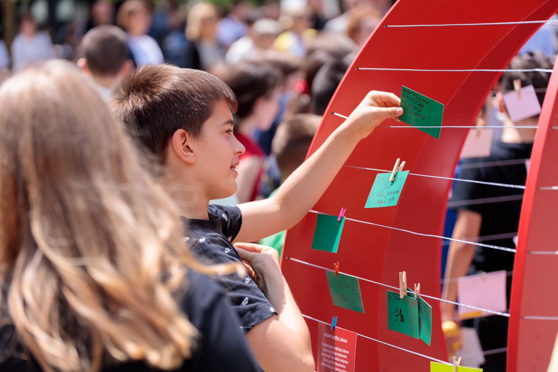 young boy reaches out to green piece of paper hanging on string 