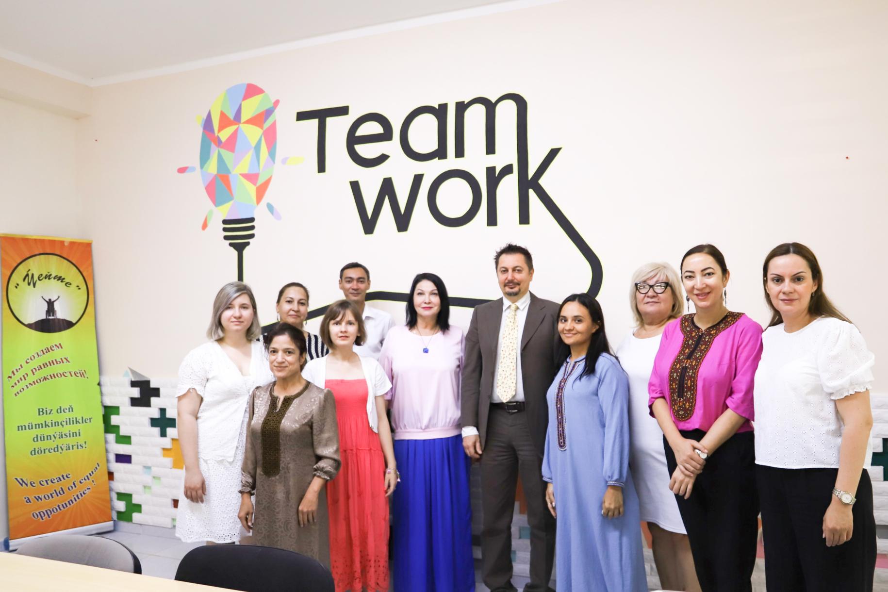 group of people stand in front of wall which says 'team work' 