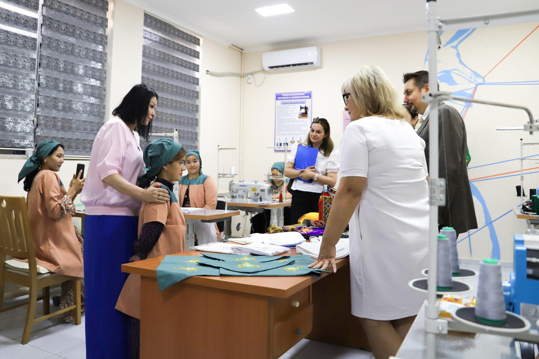A group of adults and young people talking inside a room with sewing equipment