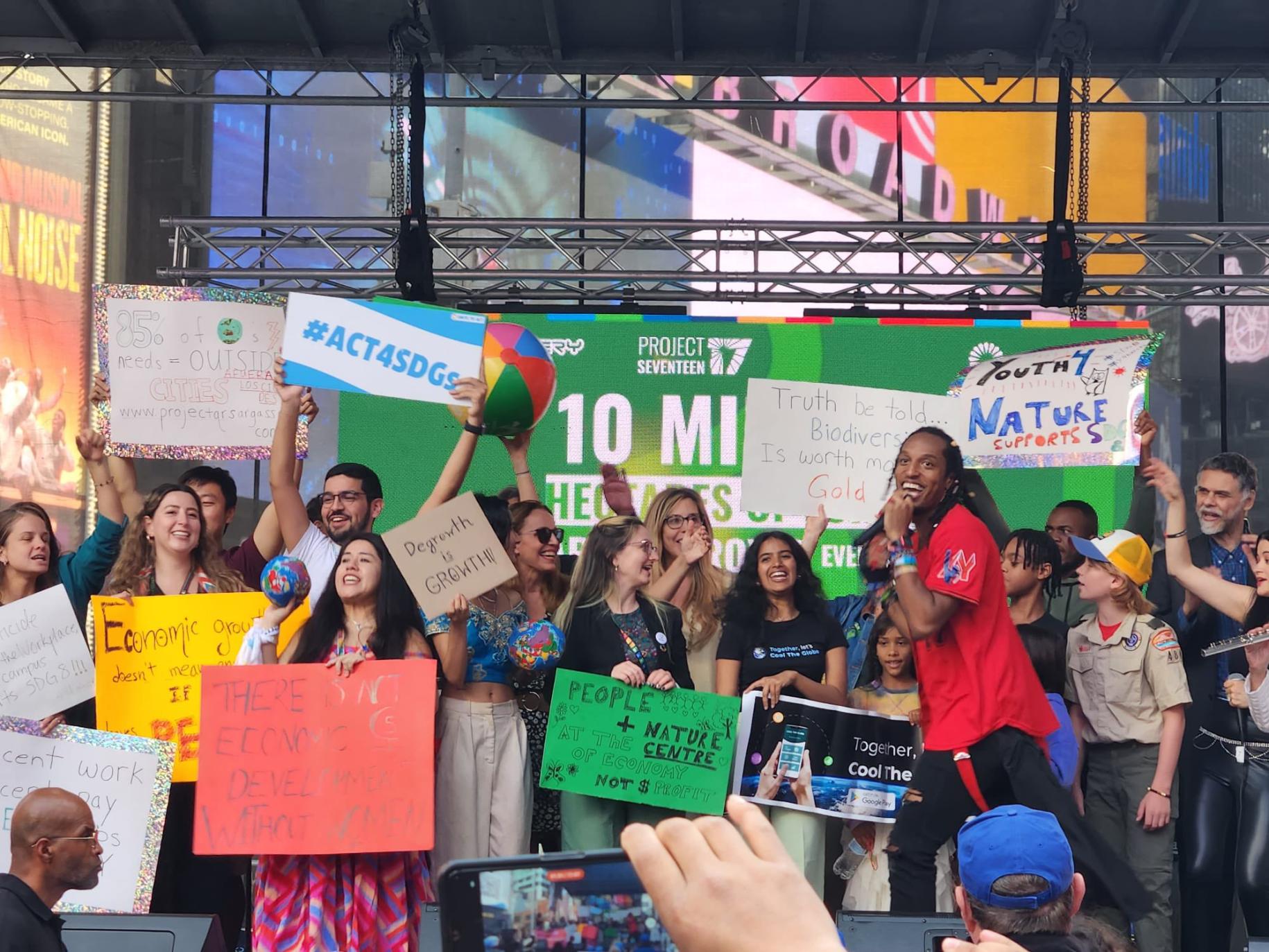 group of people on stage holding colourful posters