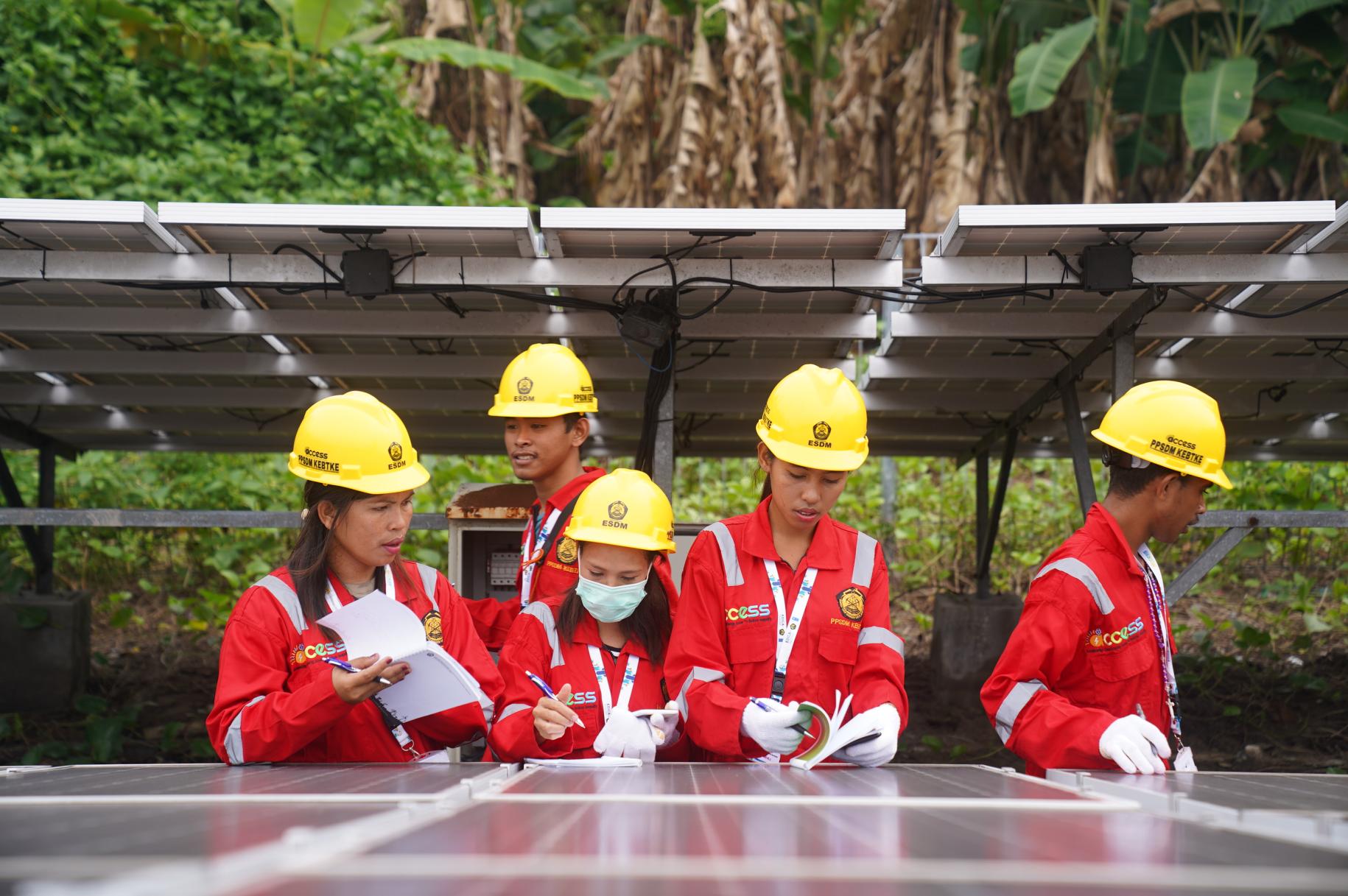 group of people in yellow hard hats and red overalls work on solar panel