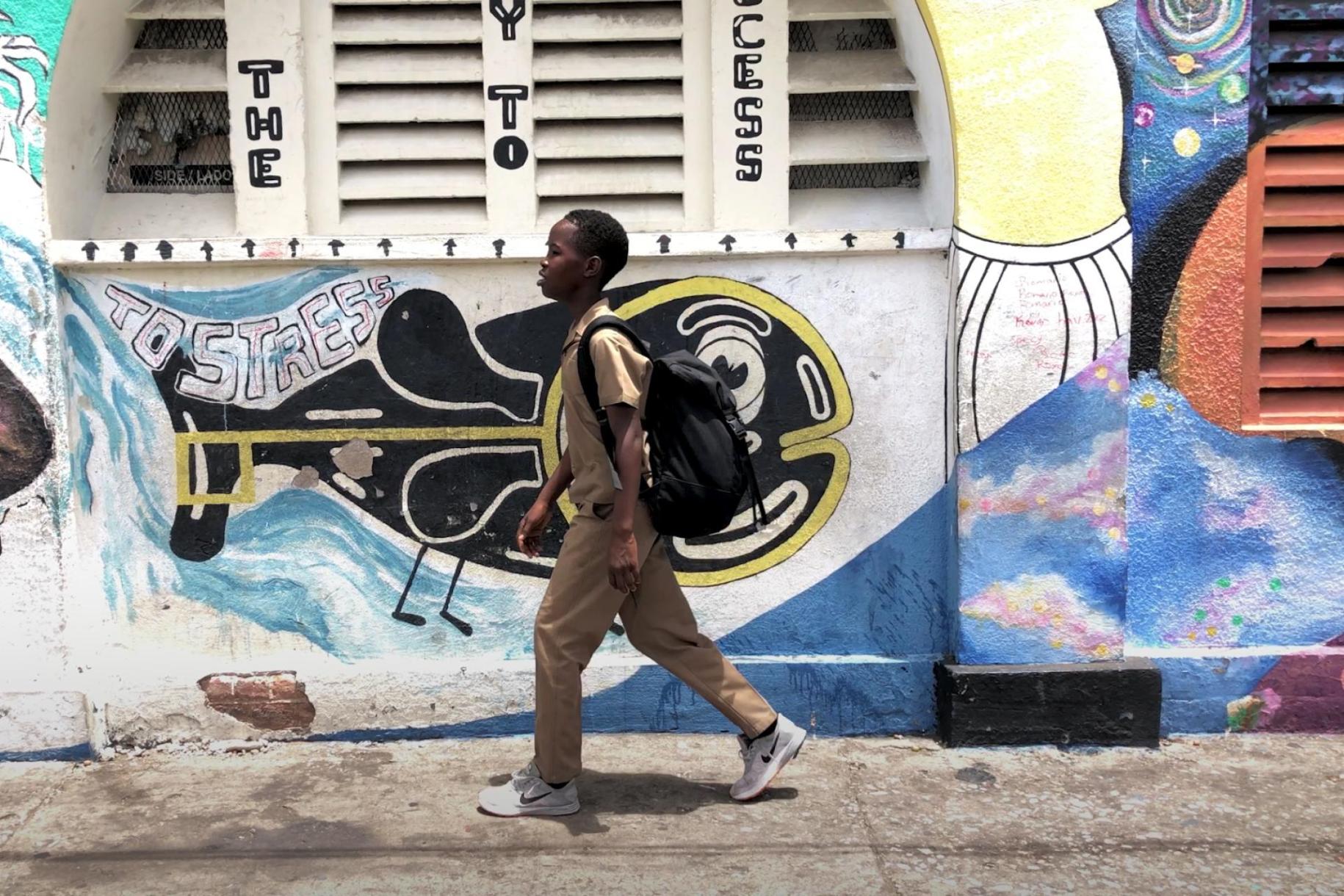 school boy walks past wall with colourful graffiti 