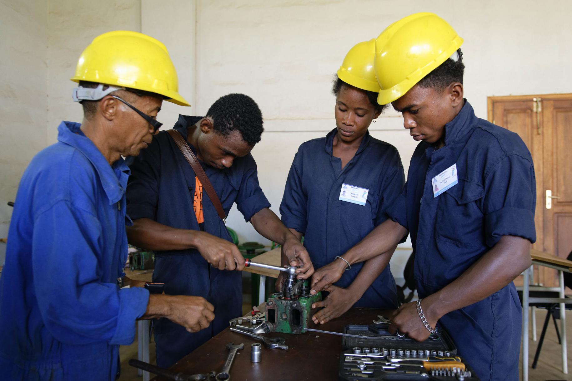 group of people in yellow hard hats work with machinery