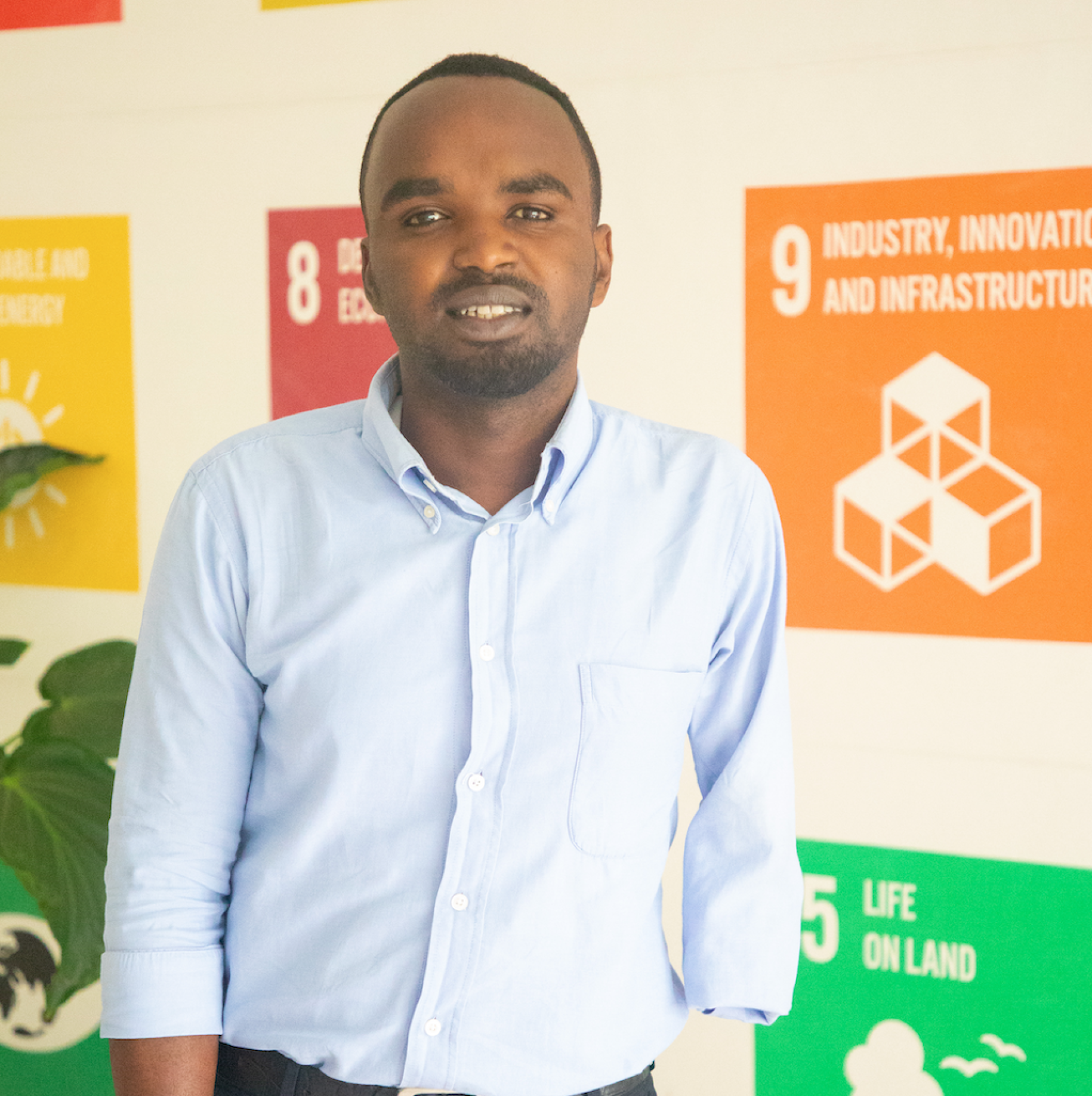Jean de Dieu Ukwishatse standing in a UN office with SDG posters in the background. 