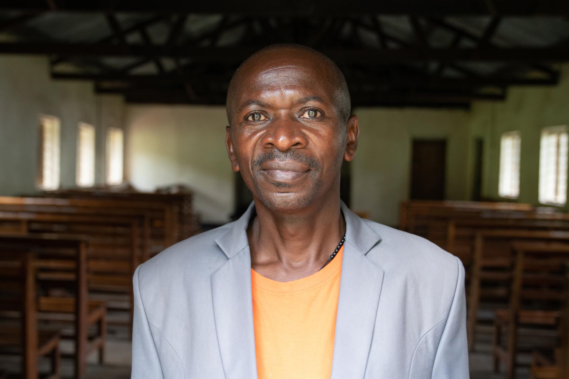 man in grey suits stand in a church looking directly into the camera