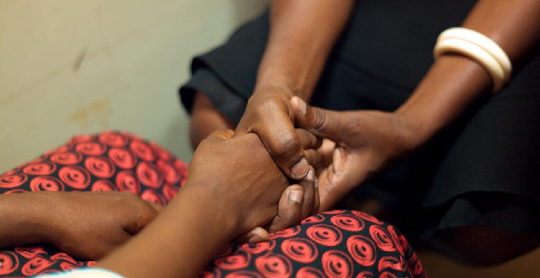 close up photo of two people sitting facing each other holding hands