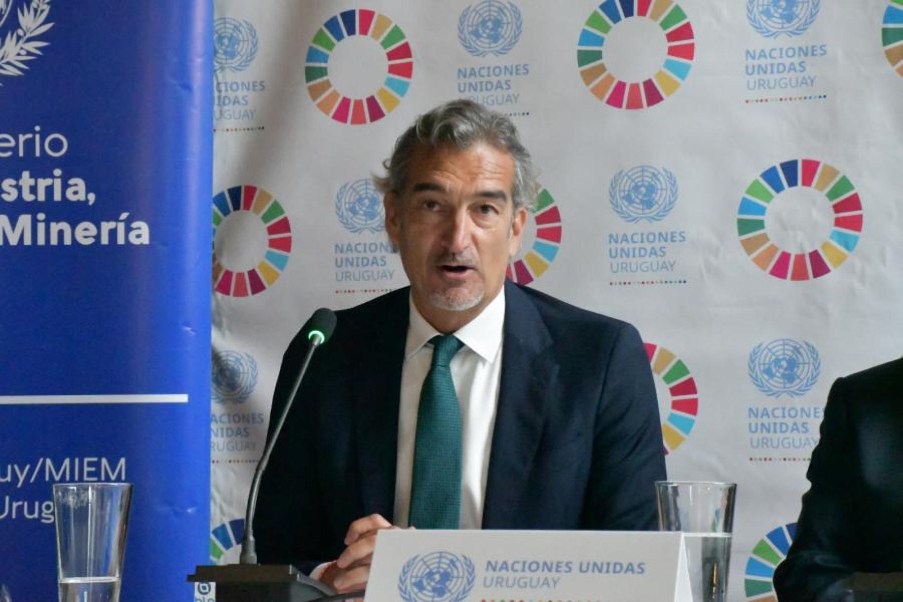 man in dark suit sits at panel discussion
