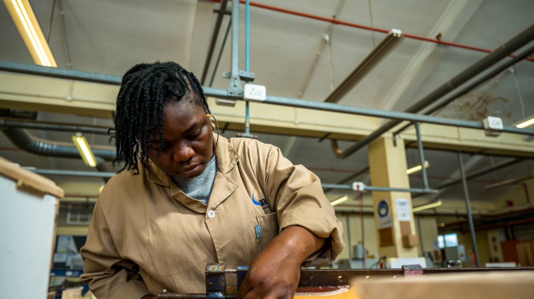 young woman in beige shirt works at a carpentry station