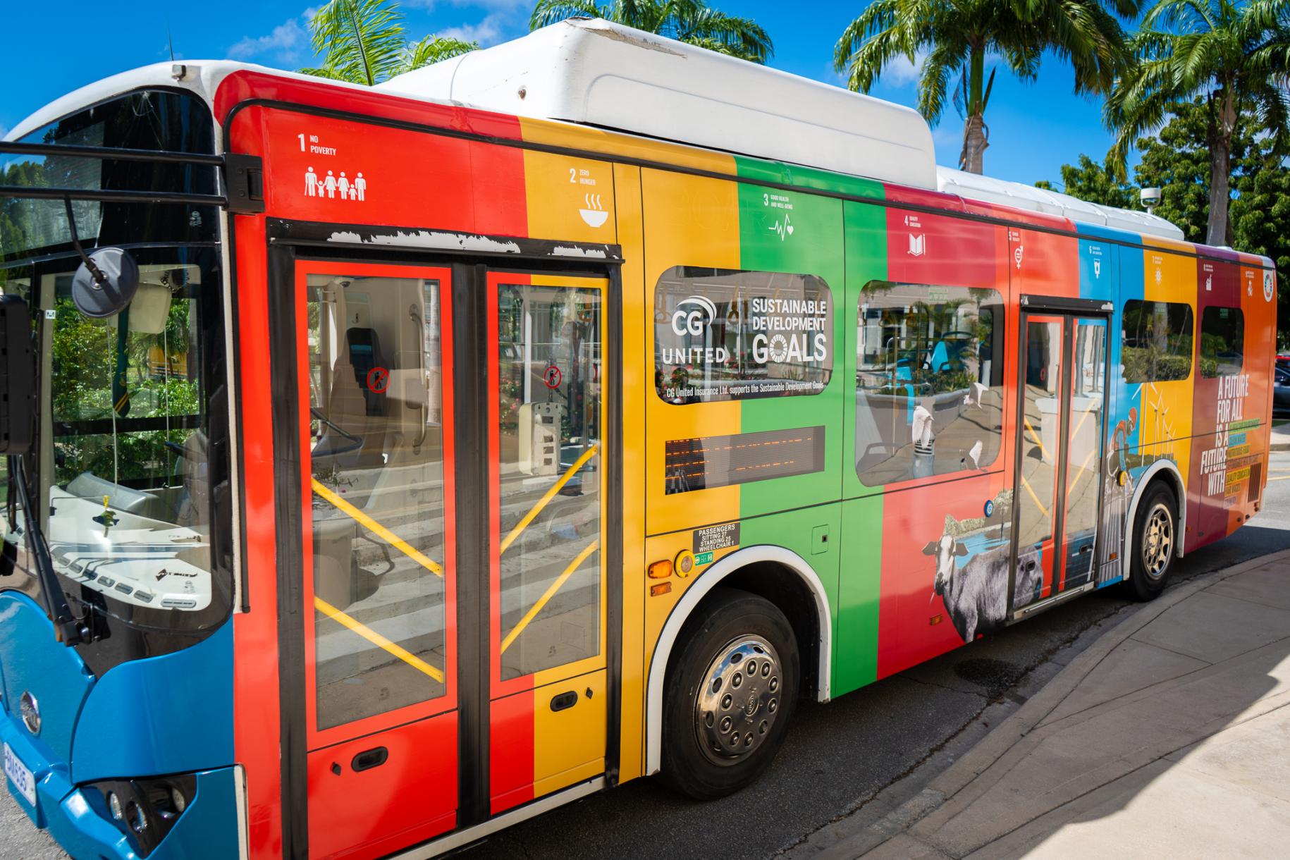 A multi-coloured bus pulls up to a kerb