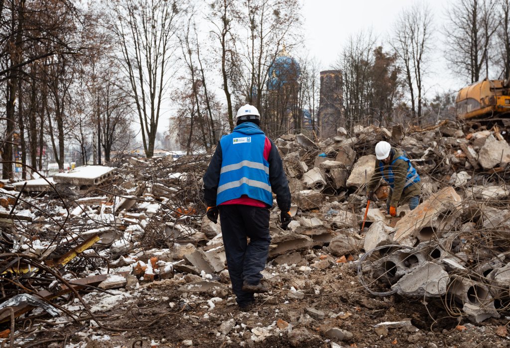 Man i n UN vest walking on rubble.