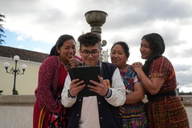 People looking at the tablet in young boy's hand.